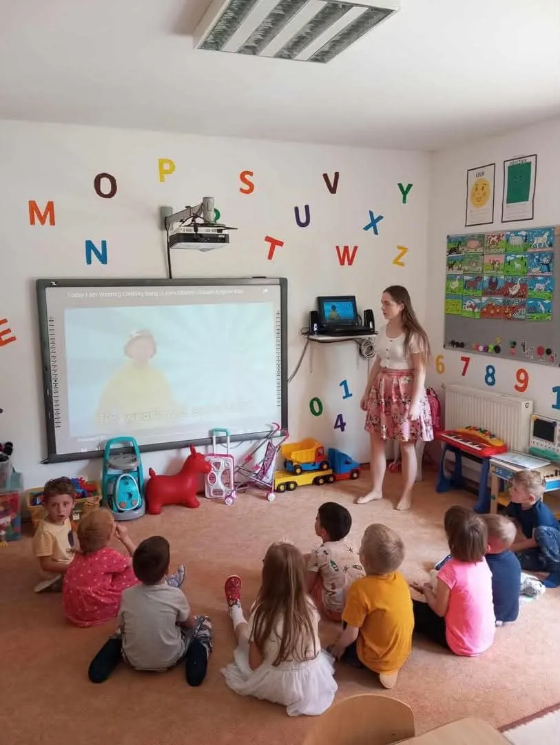 Pedagogička pracuje s deťmi pri interaktívnej tabuli v triede